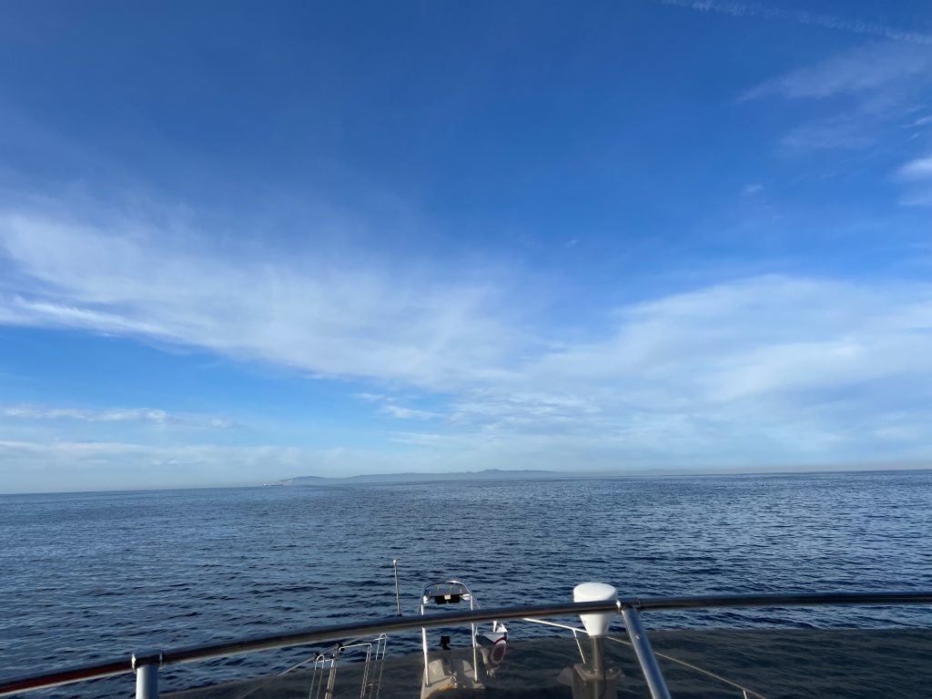 Calm ocean view from the bow of a boat in early morning light.